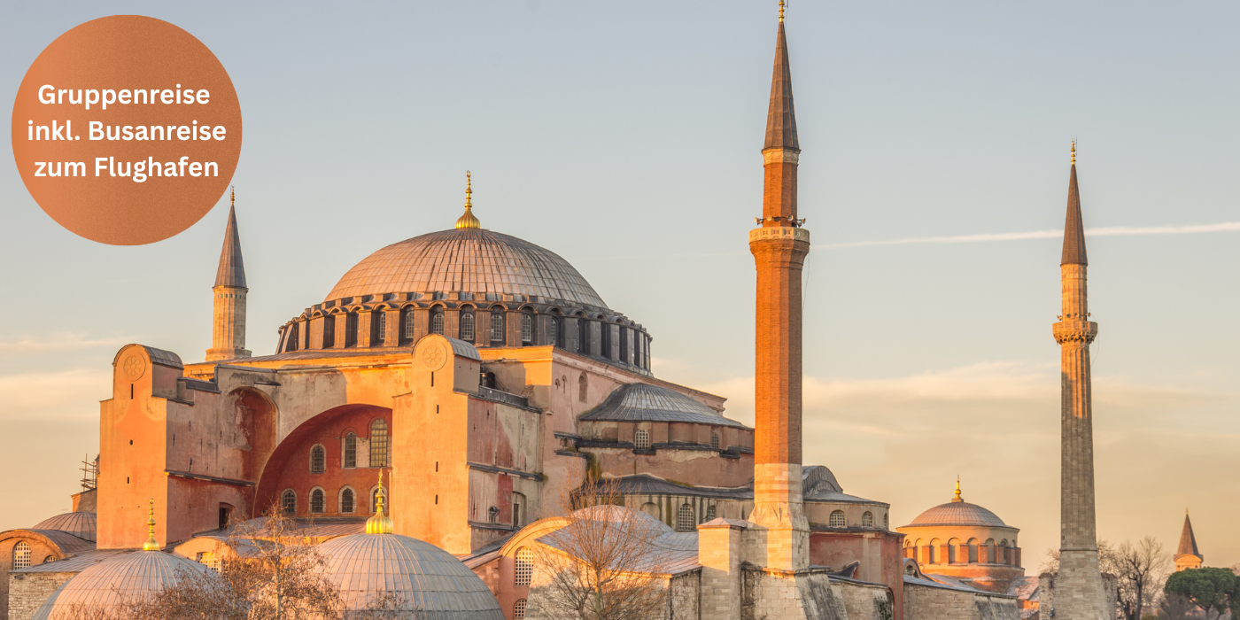 Die Hagia Sophia in Istanbul im warmen Abendlicht, mit ihren markanten Kuppeln und Minaretten; links ein orangefarbener Kreis mit dem Text „Gruppenreise inkl. Busanreise zum Flughafen“.
